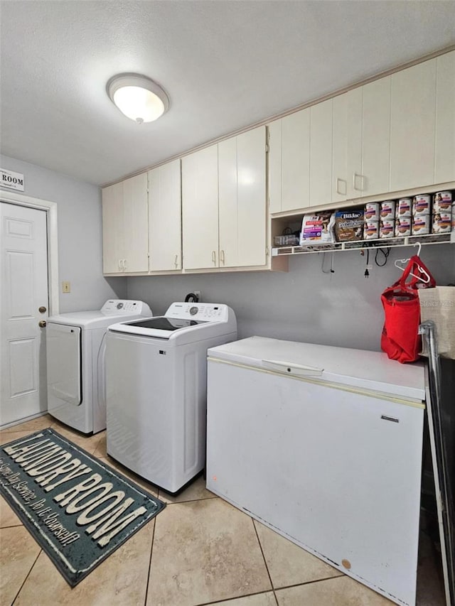 clothes washing area with cabinets, light tile patterned flooring, and independent washer and dryer