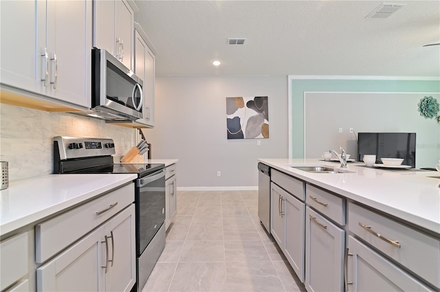 kitchen with stainless steel appliances, decorative backsplash, gray cabinets, light tile patterned floors, and sink