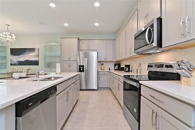 kitchen with appliances with stainless steel finishes, tasteful backsplash, an inviting chandelier, sink, and light tile patterned flooring