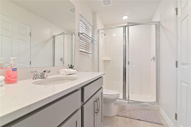 bathroom with tile patterned floors, toilet, vanity, and a shower with shower door