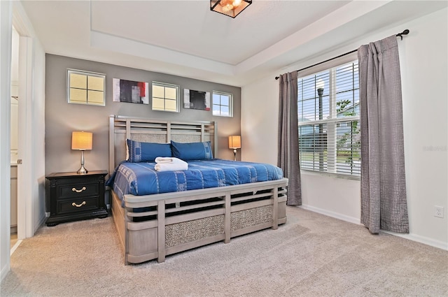 bedroom featuring light carpet and a tray ceiling