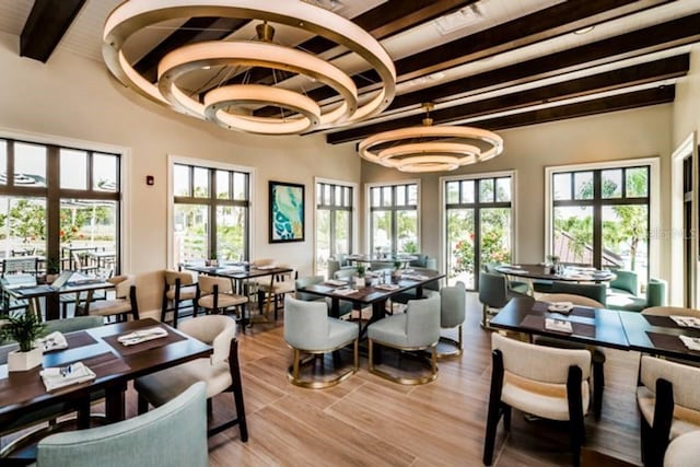 dining space featuring beamed ceiling and light hardwood / wood-style floors