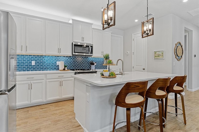 kitchen featuring white cabinets, a kitchen island with sink, and appliances with stainless steel finishes