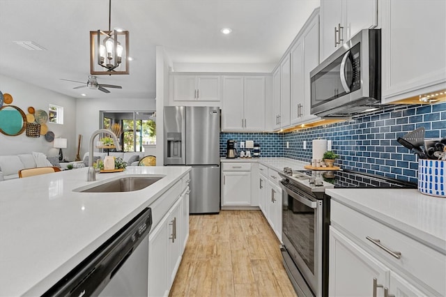 kitchen featuring appliances with stainless steel finishes, sink, white cabinetry, and pendant lighting