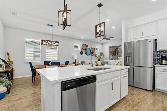 kitchen with ceiling fan, sink, white cabinetry, appliances with stainless steel finishes, and an island with sink