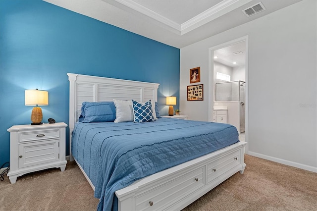 carpeted bedroom featuring ensuite bath, a tray ceiling, and ornamental molding