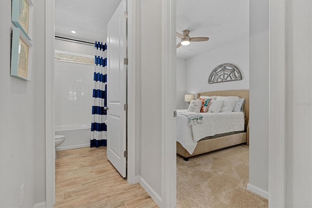 interior space with ceiling fan, a textured ceiling, toilet, and shower / bathtub combination with curtain