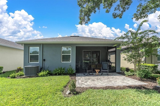 rear view of property with a patio area, a sunroom, cooling unit, and a lawn