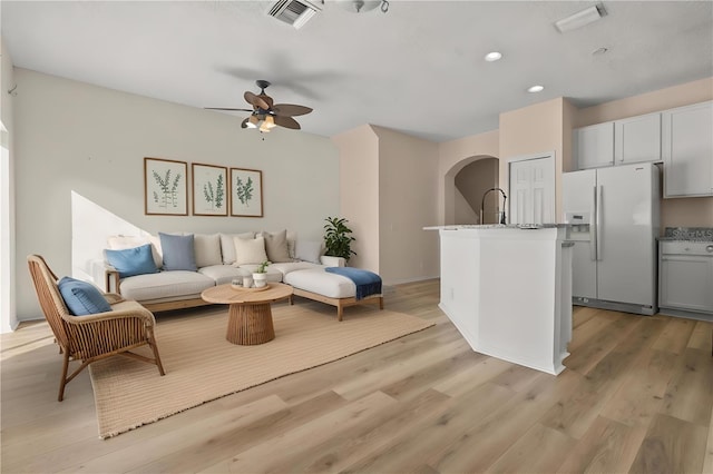 living room featuring light wood-type flooring, ceiling fan, and sink