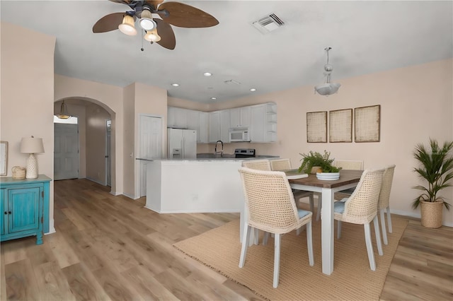 dining space with ceiling fan, light wood-type flooring, and sink