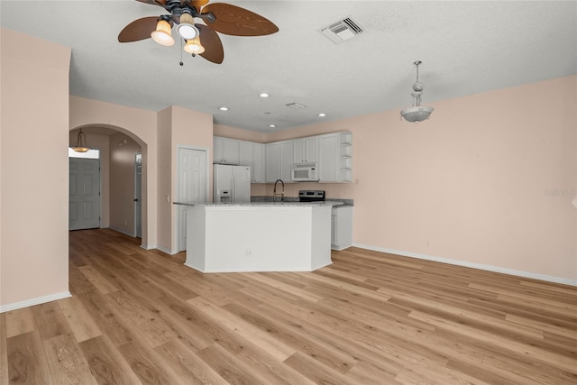 kitchen with an island with sink, ceiling fan, fridge with ice dispenser, white cabinets, and sink