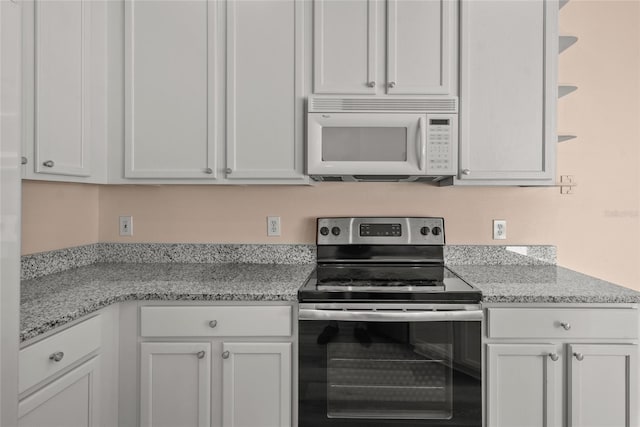 kitchen featuring stainless steel electric range, light stone countertops, and white cabinetry