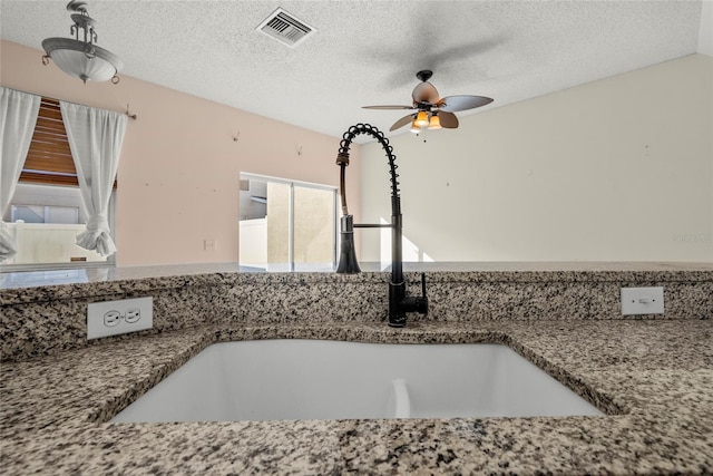 interior details featuring ceiling fan, sink, and a textured ceiling