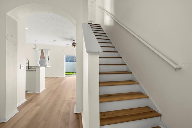 stairs featuring ceiling fan and hardwood / wood-style floors