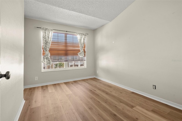 unfurnished room with light wood-type flooring and a textured ceiling