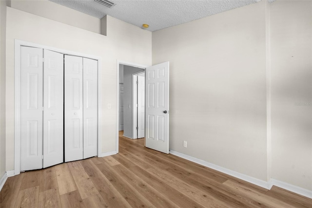 unfurnished bedroom featuring light hardwood / wood-style floors, a textured ceiling, and a closet