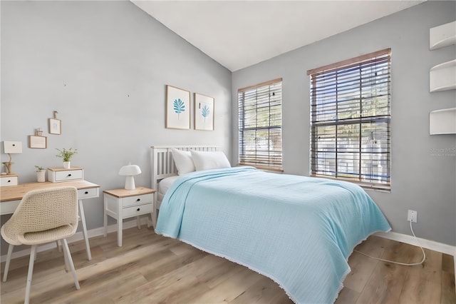 bedroom with light wood-type flooring and vaulted ceiling