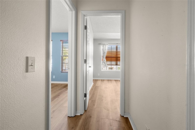 corridor featuring light hardwood / wood-style floors and a textured ceiling