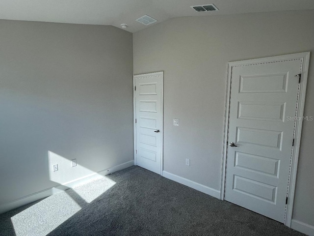 unfurnished bedroom featuring dark carpet and lofted ceiling