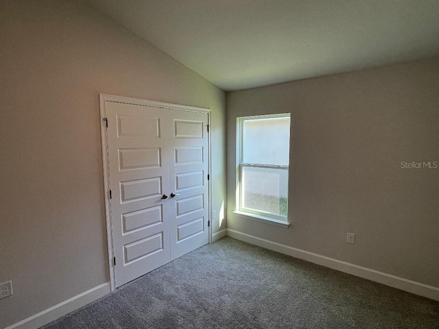 unfurnished bedroom featuring carpet flooring, vaulted ceiling, and a closet