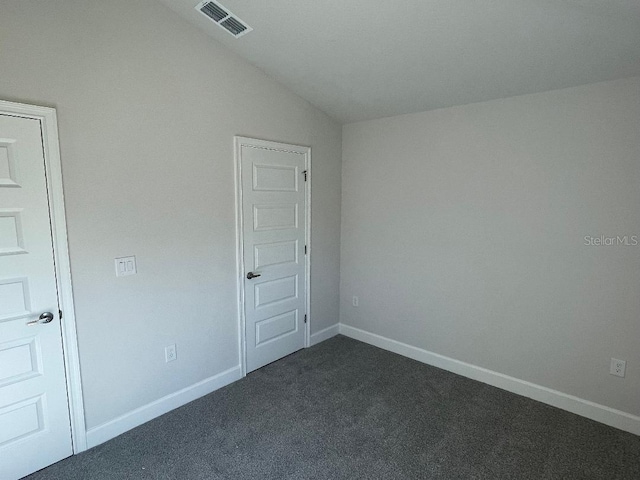 empty room with dark colored carpet and vaulted ceiling