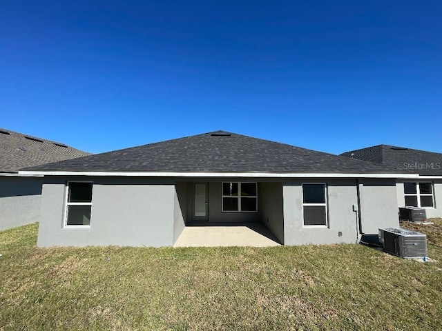 back of property with central air condition unit, a patio area, and a yard