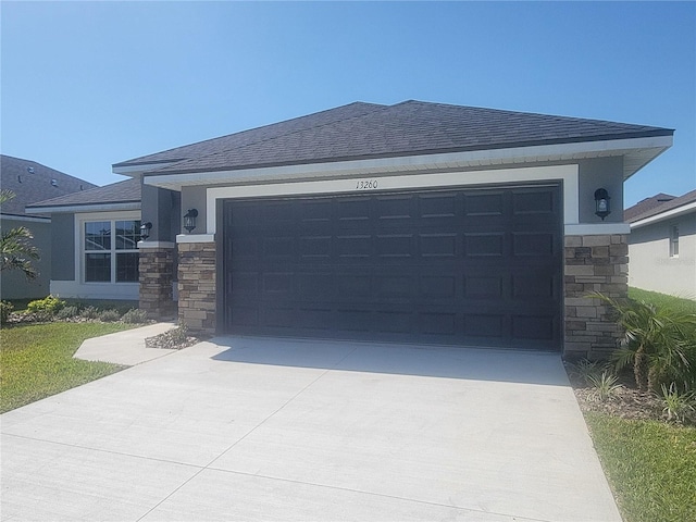 view of front of house with an attached garage, a shingled roof, stone siding, and driveway