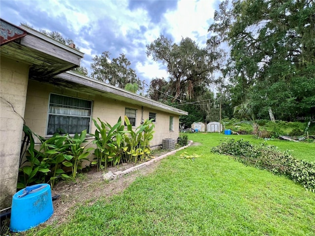 view of yard featuring a shed and central AC