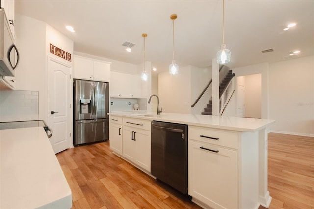 kitchen featuring a center island with sink, appliances with stainless steel finishes, tasteful backsplash, decorative light fixtures, and white cabinets