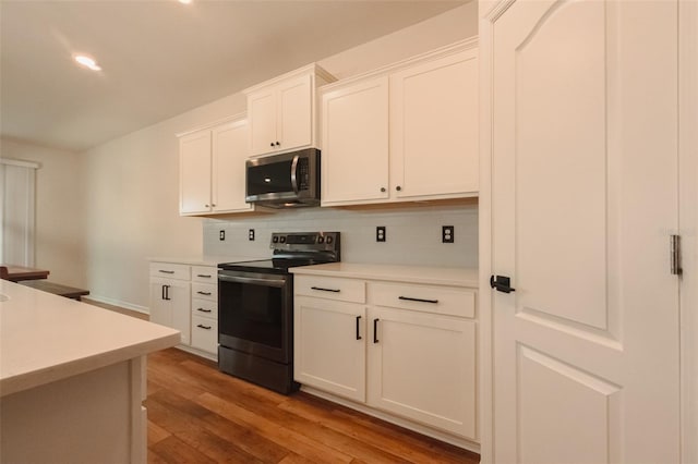 kitchen featuring tasteful backsplash, hardwood / wood-style floors, stainless steel appliances, and white cabinetry