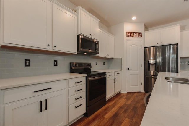 kitchen with appliances with stainless steel finishes, decorative backsplash, dark hardwood / wood-style flooring, white cabinets, and sink