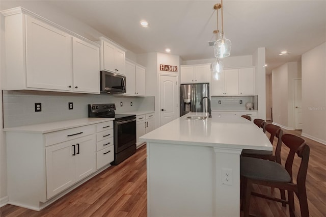 kitchen with sink, white cabinetry, appliances with stainless steel finishes, an island with sink, and a breakfast bar area