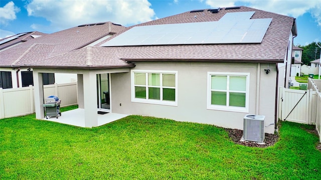 back of property with a patio area, central AC, a yard, and solar panels