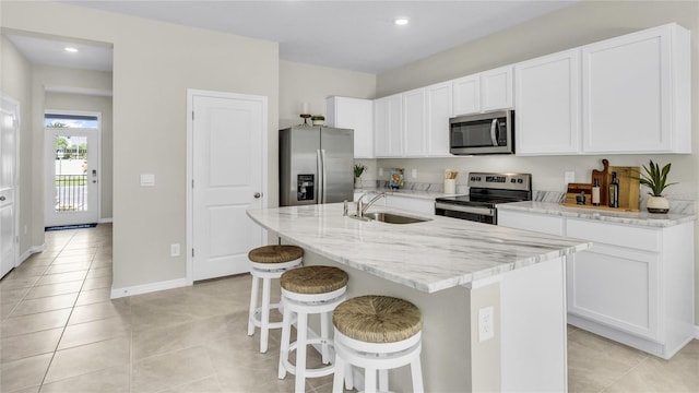 kitchen with appliances with stainless steel finishes, white cabinets, a center island with sink, and sink