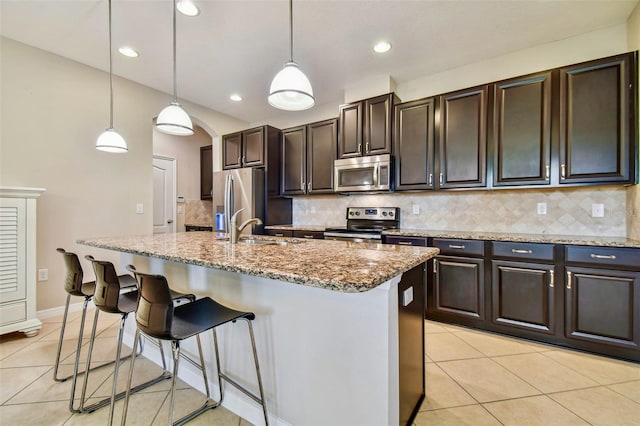 kitchen with appliances with stainless steel finishes, sink, pendant lighting, and a center island with sink