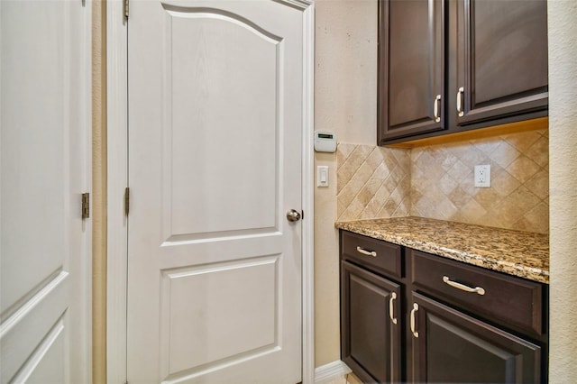 kitchen with light stone counters, decorative backsplash, and dark brown cabinets