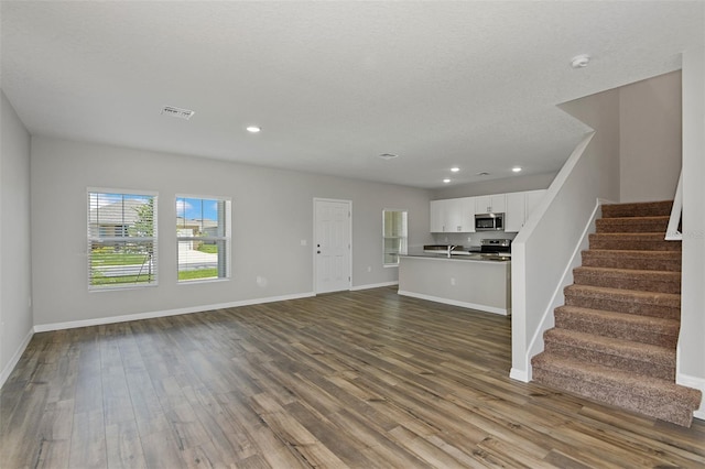 unfurnished living room featuring sink, hardwood / wood-style floors, and a textured ceiling