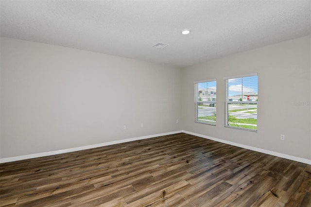 unfurnished room featuring a textured ceiling and dark hardwood / wood-style flooring