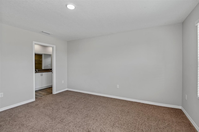 carpeted empty room featuring a textured ceiling