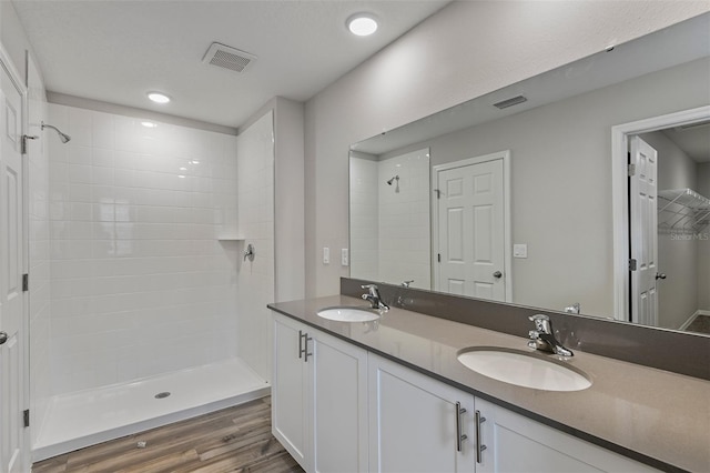 bathroom with vanity, wood-type flooring, and a tile shower