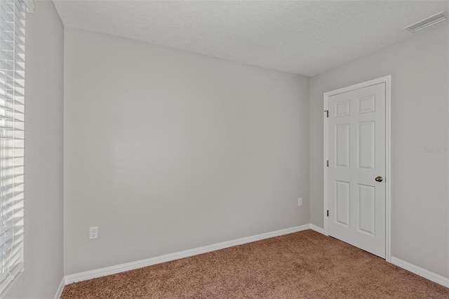 unfurnished room with a healthy amount of sunlight, carpet floors, and a textured ceiling