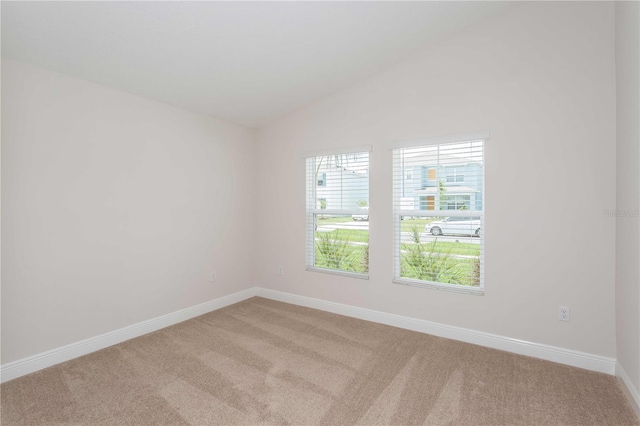 carpeted empty room featuring vaulted ceiling