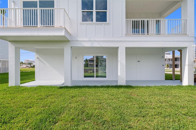 view of exterior entry with a balcony and a lawn