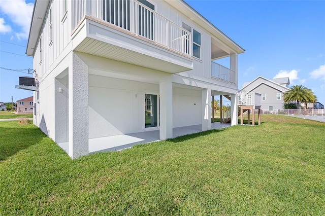 rear view of house with a balcony and a lawn