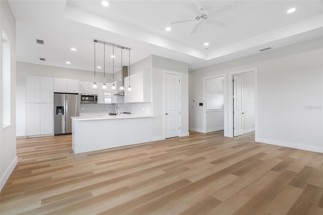 kitchen featuring a raised ceiling, white cabinetry, appliances with stainless steel finishes, and pendant lighting