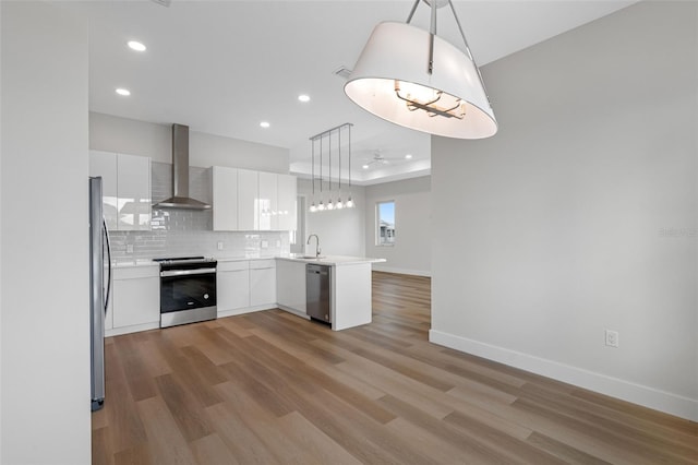 kitchen with wall chimney exhaust hood, white cabinetry, decorative light fixtures, kitchen peninsula, and stainless steel appliances