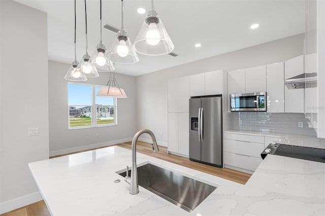 kitchen featuring decorative light fixtures, tasteful backsplash, sink, white cabinets, and stainless steel appliances