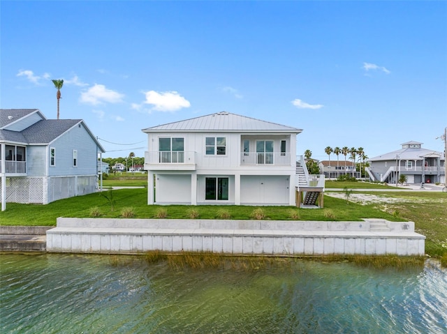 back of house featuring a water view, a balcony, and a lawn