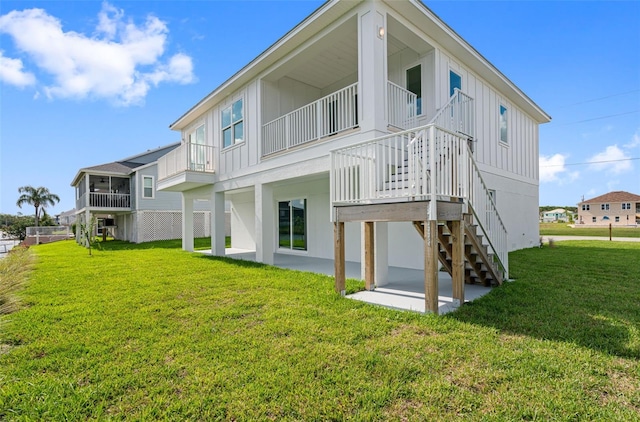 rear view of house with a patio area, a balcony, and a lawn