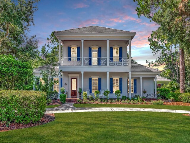 view of front of house with a lawn, a balcony, and a porch